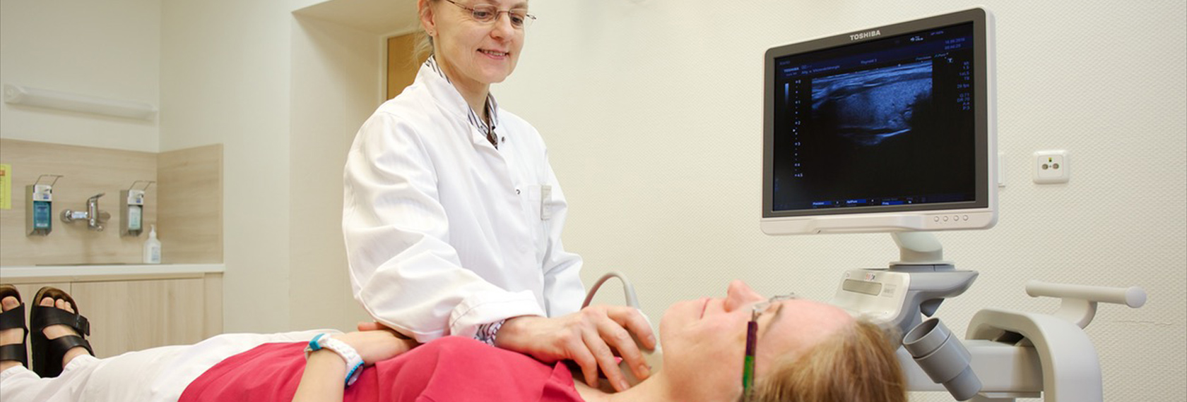 Ärztin untersucht die Schildrüse der Patientin mit einem Ultraschall